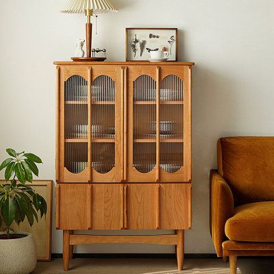 a wooden cabinet sitting next to a chair in a living room with a lamp on top of it