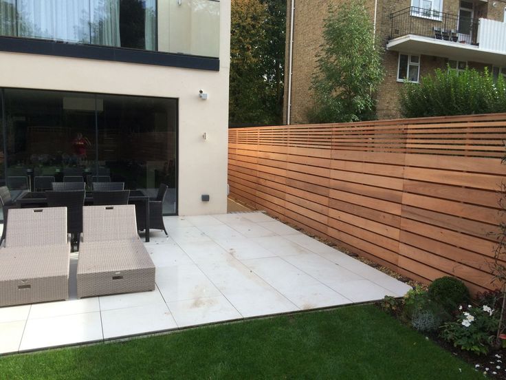 an outdoor patio with wooden slats and chairs next to a fenced in area