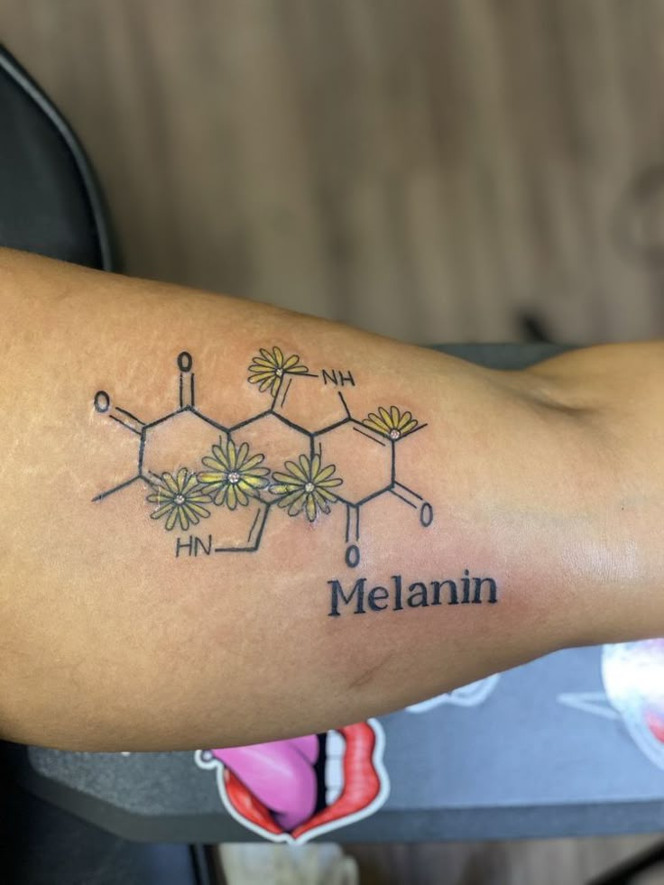 a tattoo with the name melanin written on it's arm and flowers