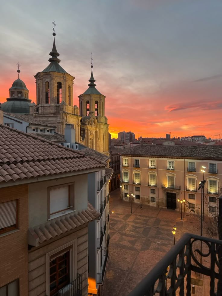 the sun is setting over an old city with tall buildings and steeple spires