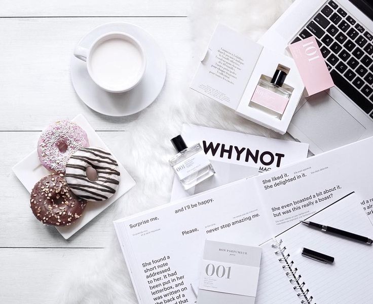 a white table topped with notebooks and donuts next to a cup of coffee