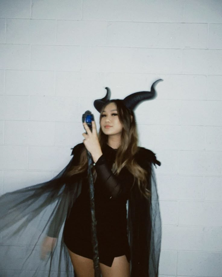 a woman dressed up as a devil holding a cell phone