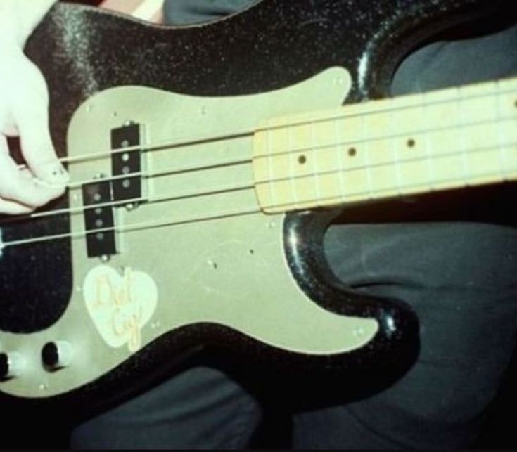 a close up of a person playing an electric bass guitar with their hands on it