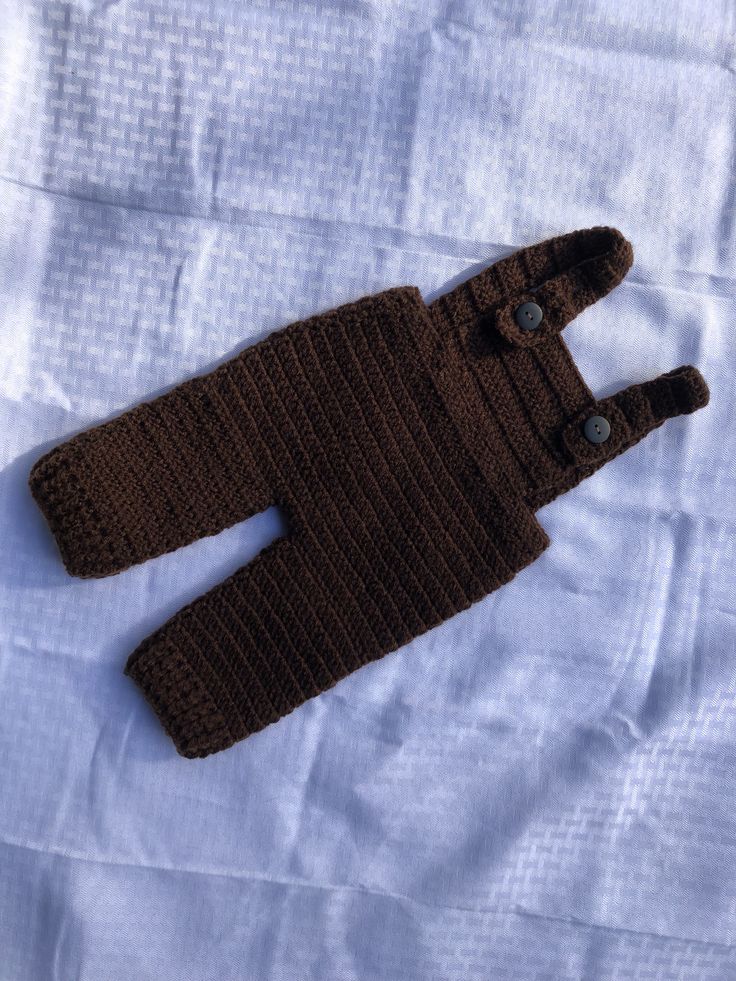 a brown knitted sweater laying on top of a white sheet