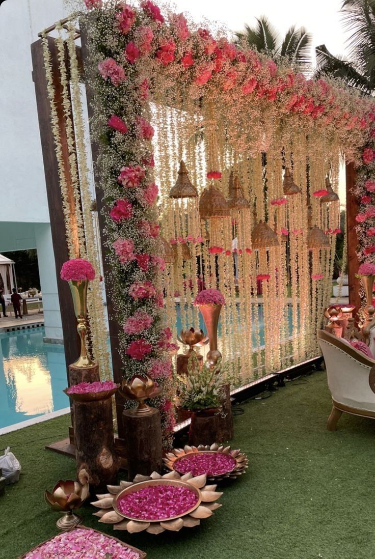 an outdoor wedding setup with flowers and decorations on the grass next to a swimming pool