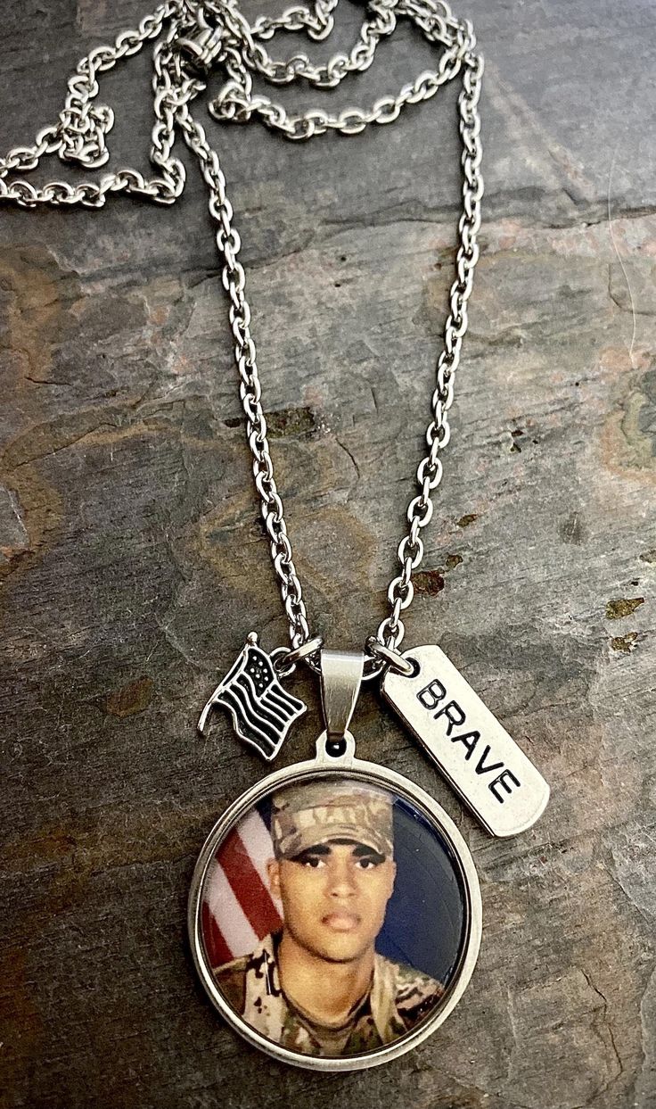 "This necklace is made on your choice of a 1\" or 3/4\" stainless steel pendant and includes two accent charms (flag and Brave charms). The chain is made with stainless steel that can be made in the length of your choice (24\", 26\", 28\", or 30\"). It can be made on a 3/4\" or 1\" pendant (default is 3/4\" unless noted otherwise in customer notes). INCLUDES: - Photo charm pendant - Brave charm - Flag charm - Options are available to purchase additional custom charms such as a photo, name, or da Navy Coast Guard, Air Force Gifts, Military Photos, Photo Charms, Memorial Necklace, Custom Charms, Photo Memories, Coast Guard, Stainless Steel Pendant