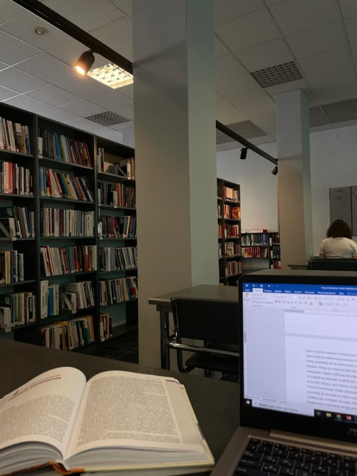 an open laptop computer sitting on top of a desk in front of a book shelf