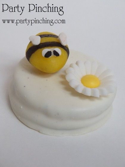 a yellow and black bee sitting on top of a white frosted cake covered in icing