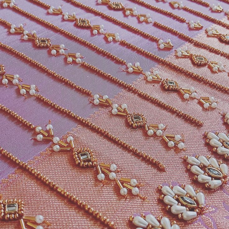 several rows of gold and pearled necklaces on a pink fabric with white beads