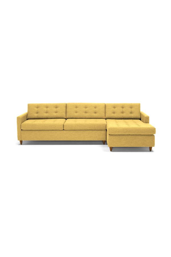 a yellow sectional couch sitting on top of a white floor