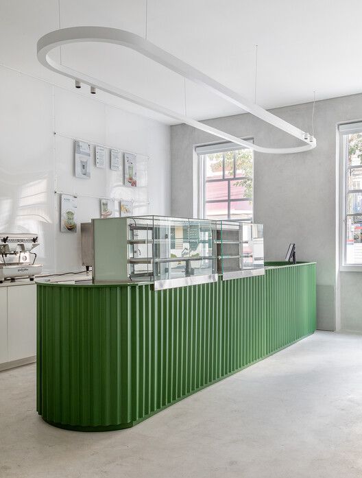 a green counter in a white room with windows and pictures on the wall behind it