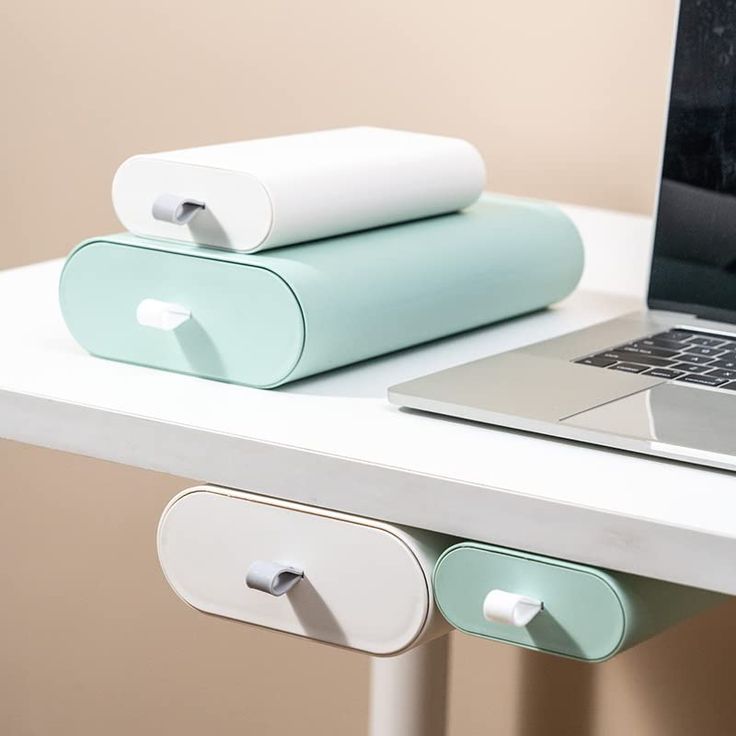 an open laptop computer sitting on top of a white desk next to two rolled up papers