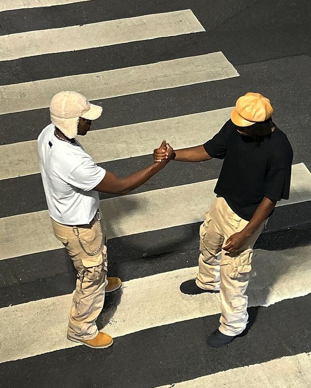 two men standing in the middle of a cross walk holding each other's hands