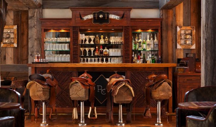 an old fashioned bar with saddles and bottles