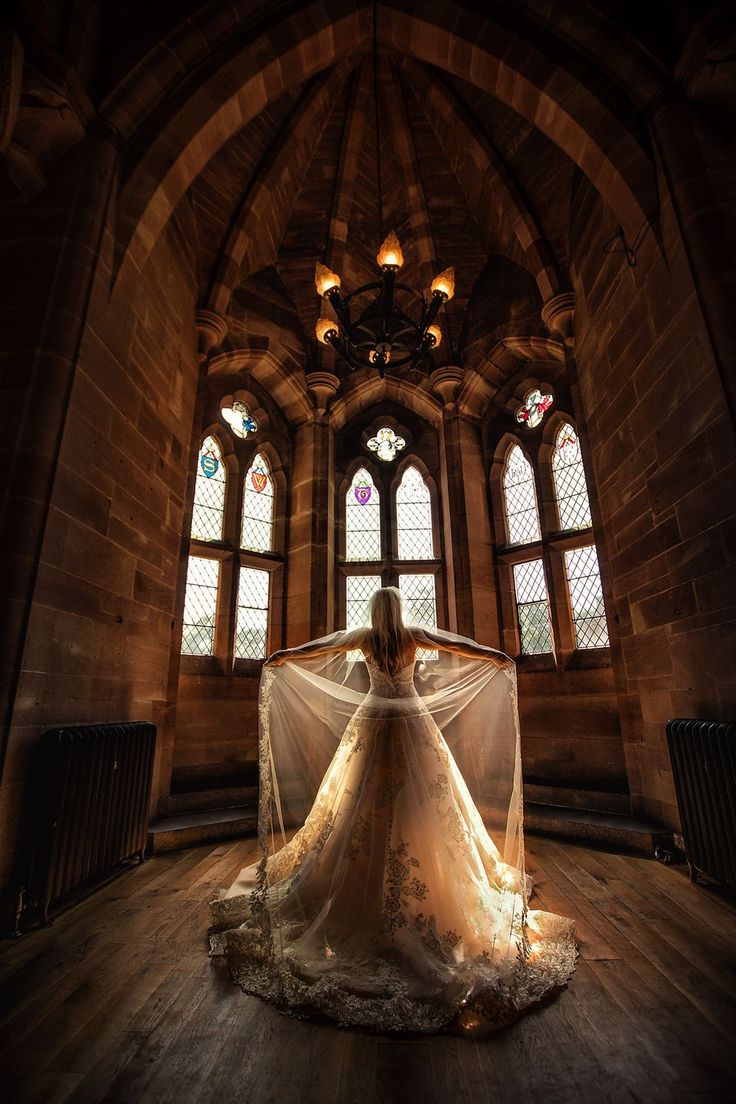 a woman in a wedding dress sitting on the floor with her veil over her head