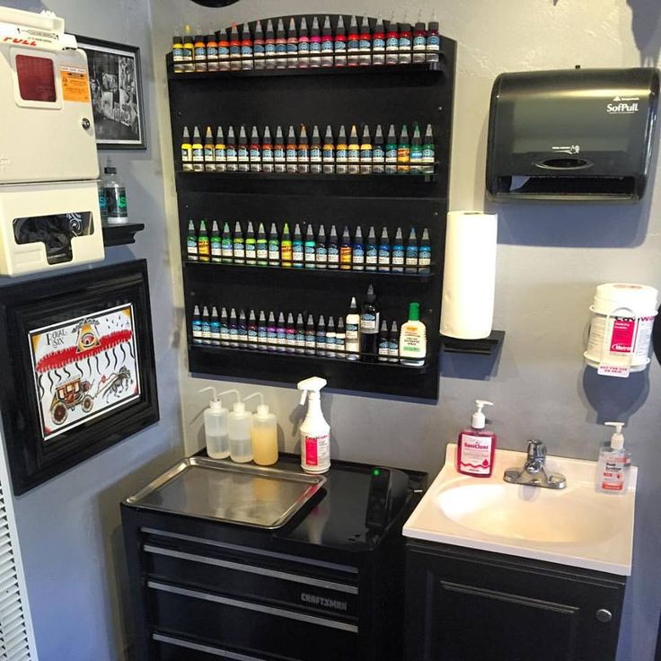 a bathroom with a sink and shelves filled with different types of nail polish on the wall