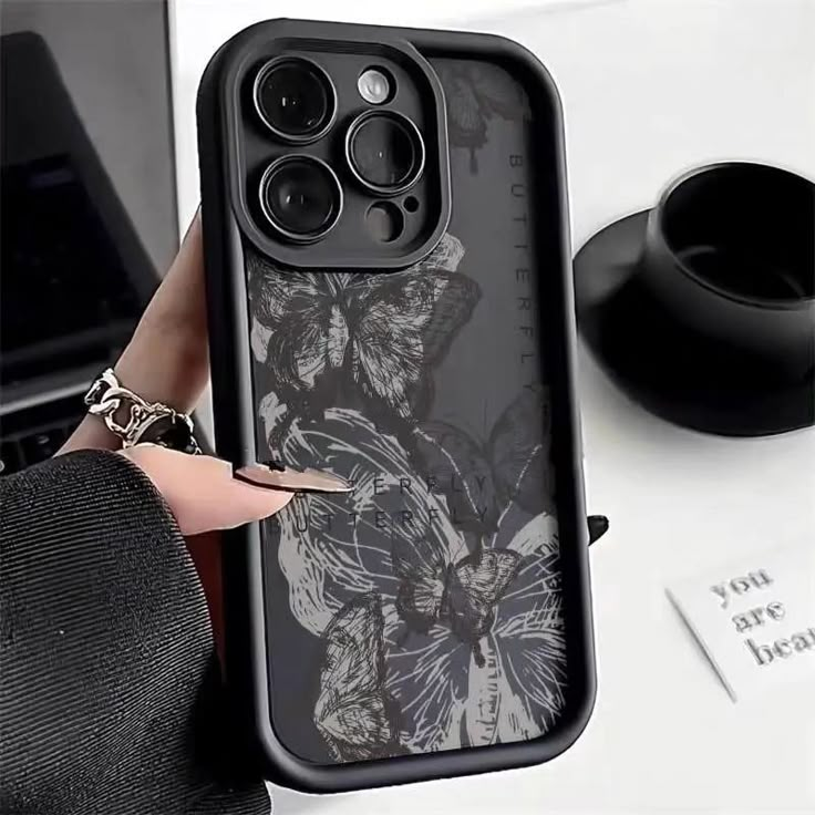 a woman is holding an iphone case with butterflies on it and the phone cover has a black