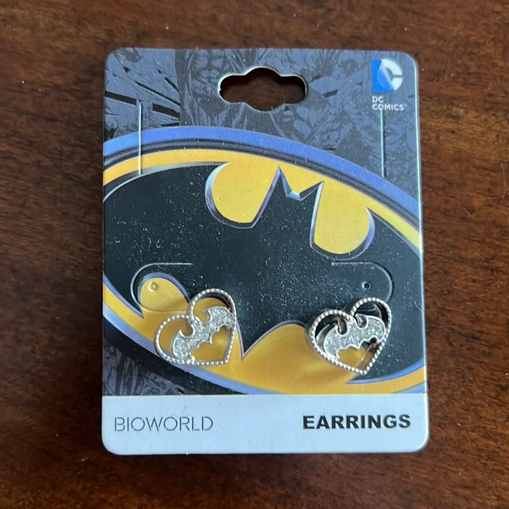 the batman earring is on top of a card with two hearts attached to it