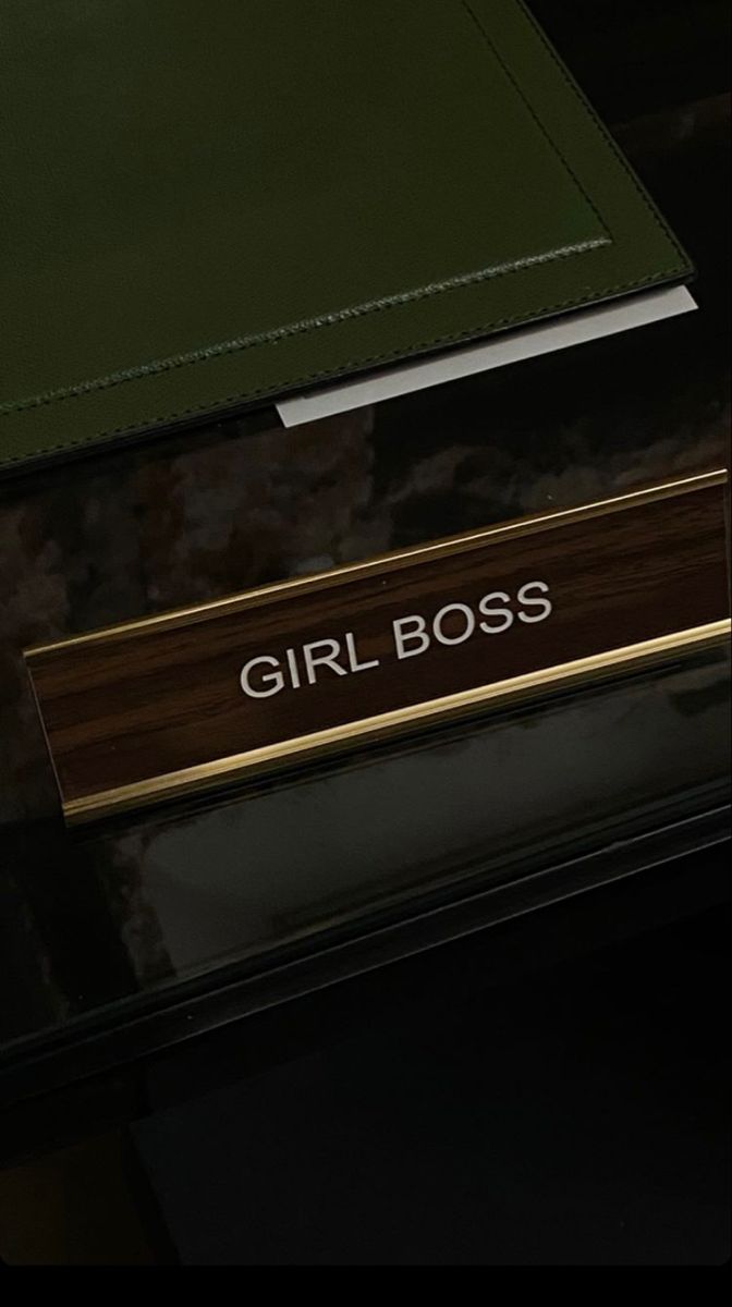 the girl boss name plate is on top of a black box with gold trimmings