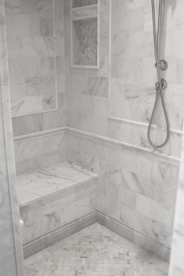 a bathroom with marble walls and flooring, shower head and hand held showerhead