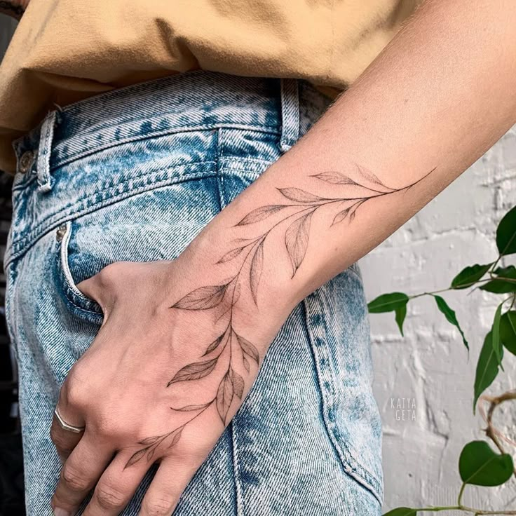 a person's hand with a tattoo on it that has leaves coming out of it