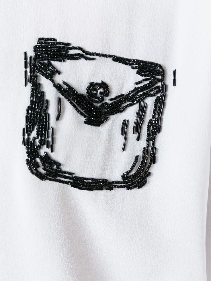 a white t - shirt with black beading on it