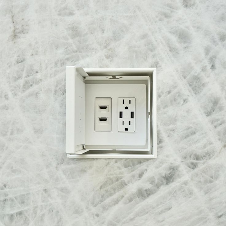 an electrical outlet in the middle of a white marble wall with two black and one white outlets