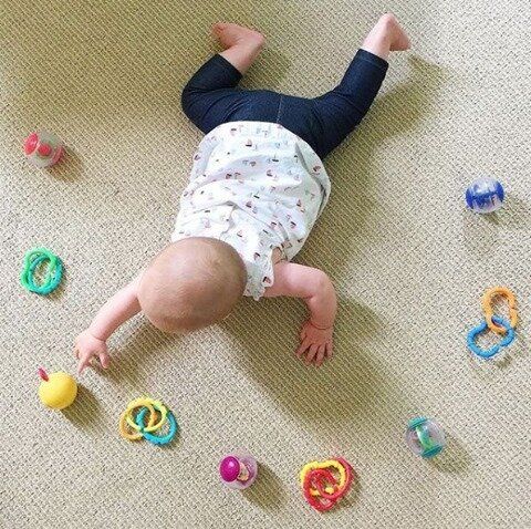 a baby laying on the floor surrounded by toys