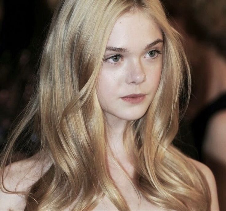 a young woman with long blonde hair wearing a strapless dress and looking at the camera