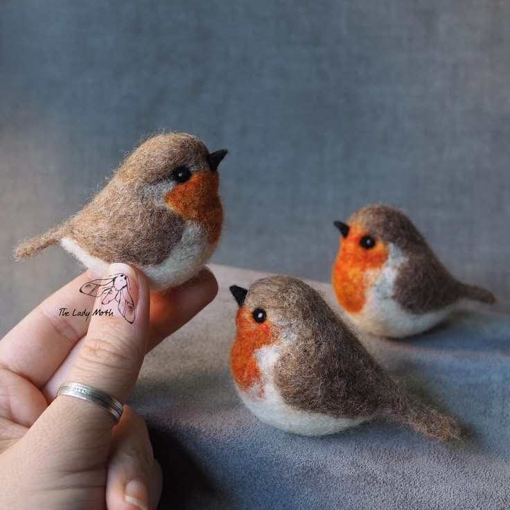 three small birds sitting on top of a table next to someone's fingernail