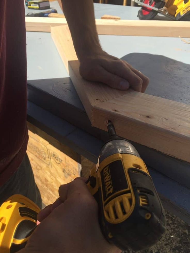 a man is using a drill to attach the boards on top of a building site