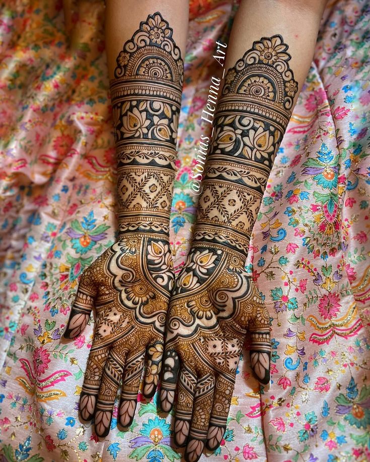 two hands with henna tattoos on them, one is showing the intricate design and the other has floral designs