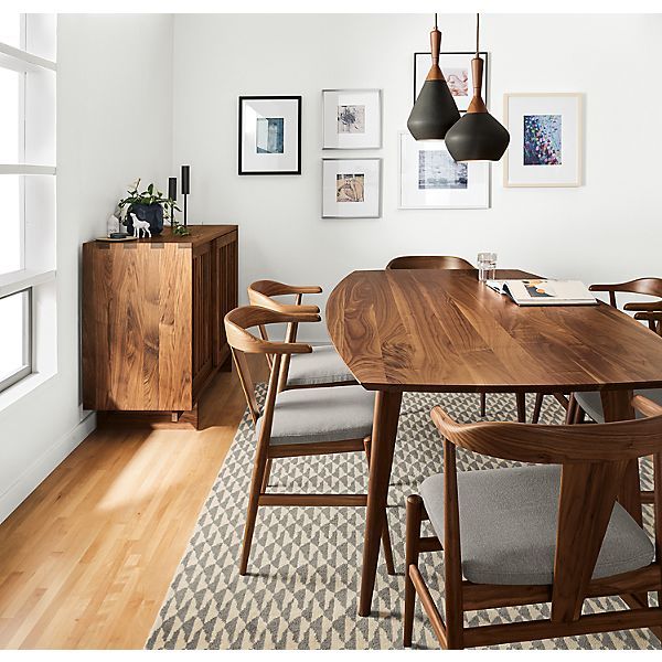 a dining room table with chairs and pictures on the wall above it, along with an area rug