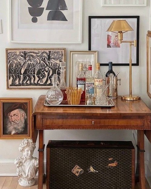 there is a table with bottles and pictures on the wall next to an old trunk