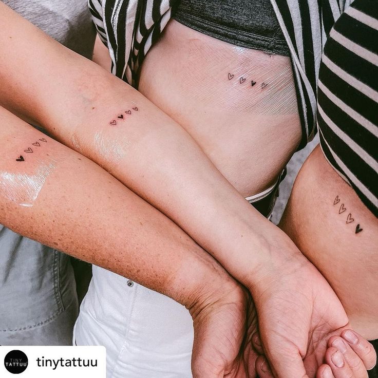 two people with tattoos on their arms holding each other's hands and looking at the camera