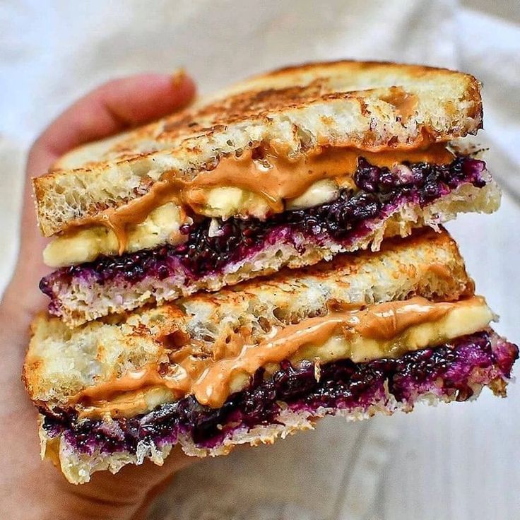 a person holding a sandwich with peanut butter and jelly