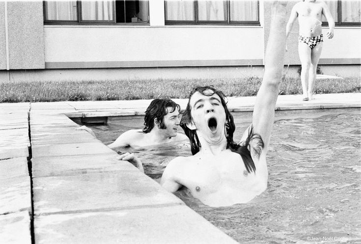 two children are playing in the pool with their feet up and one child has his mouth open