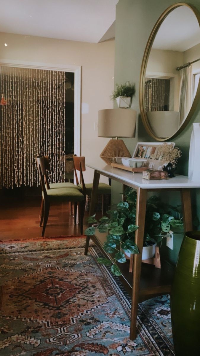 a living room filled with furniture and a large mirror on top of a table in front of a doorway