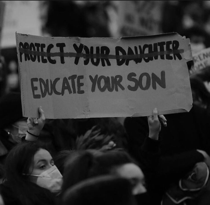 a group of people holding signs and wearing masks