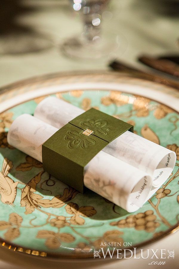 two napkins sitting on top of a green and gold plate