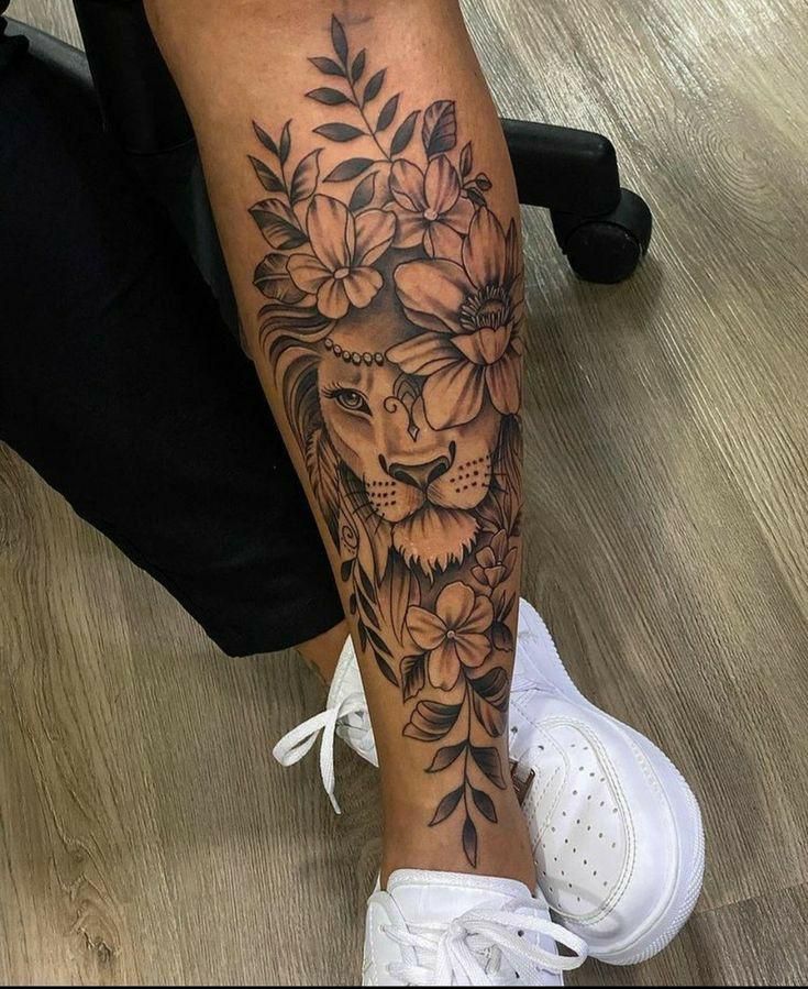 a woman's leg with flowers and a lion tattoo on her left calf area