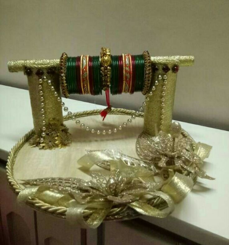 an elaborately decorated tray with gold, green and red bracelets on it's sides