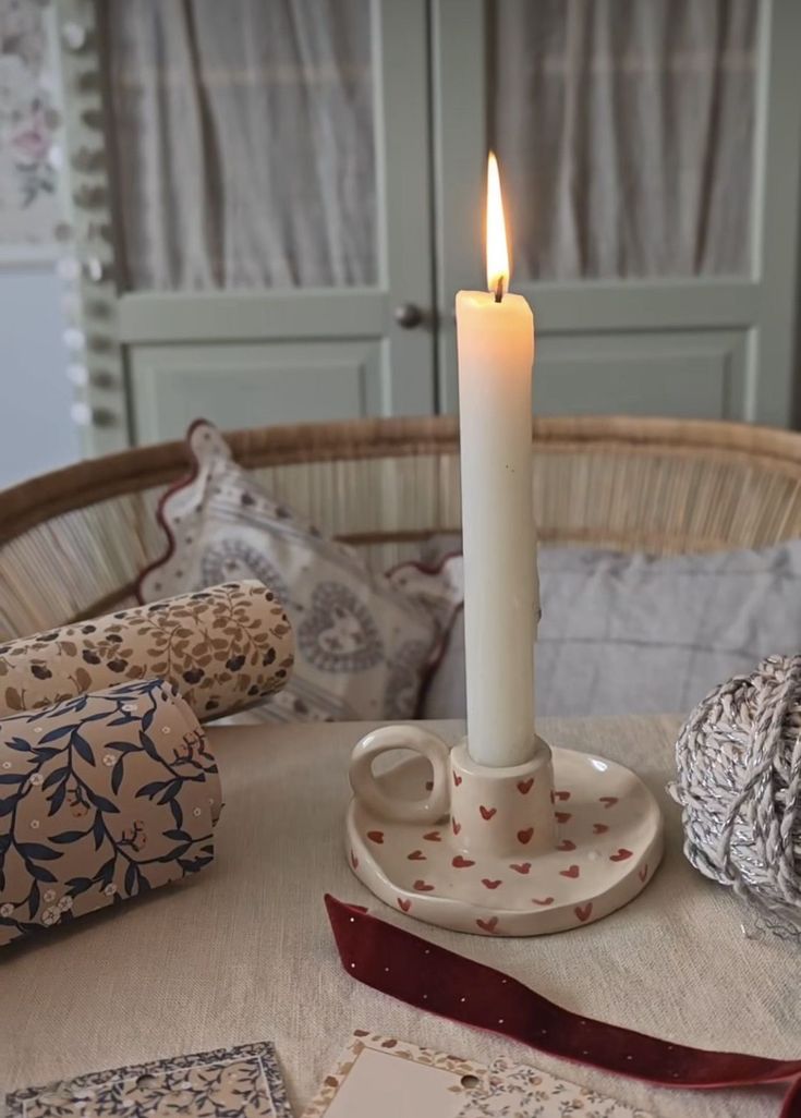 a lit candle sitting on top of a table next to some pillows and other items