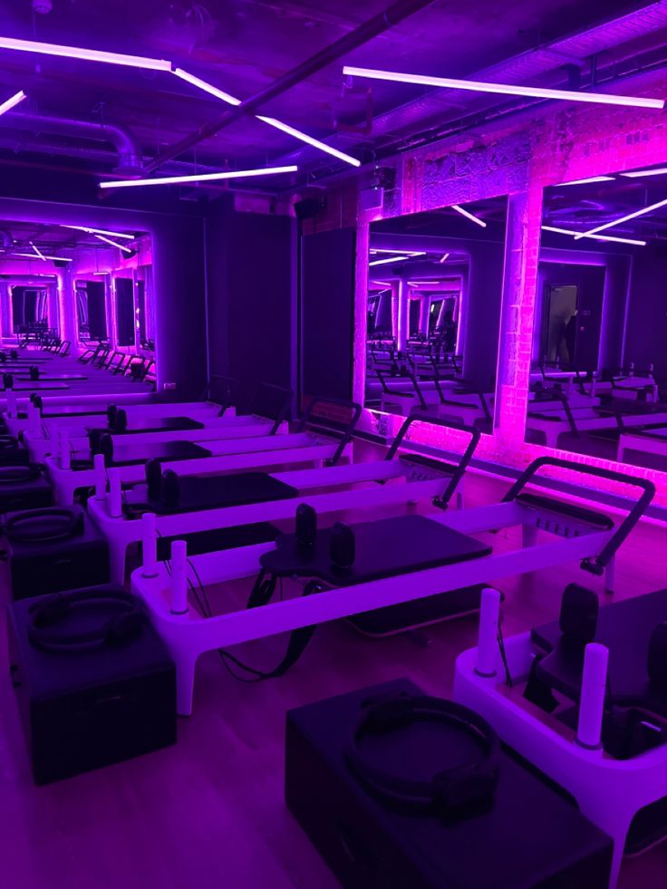 a gym with rows of treadmills and purple lighting