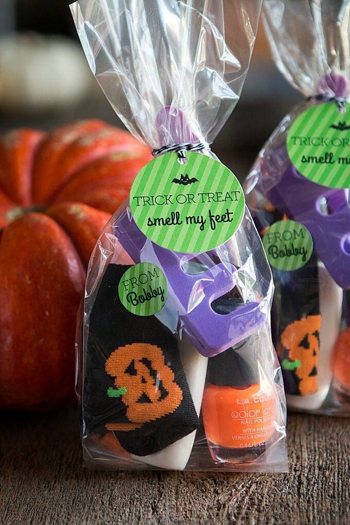 three halloween treats in plastic bags on a table with pumpkins and other items behind them