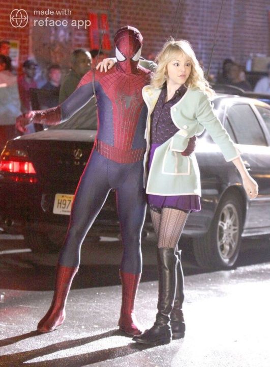 a woman standing next to a spider man in front of a car on the street