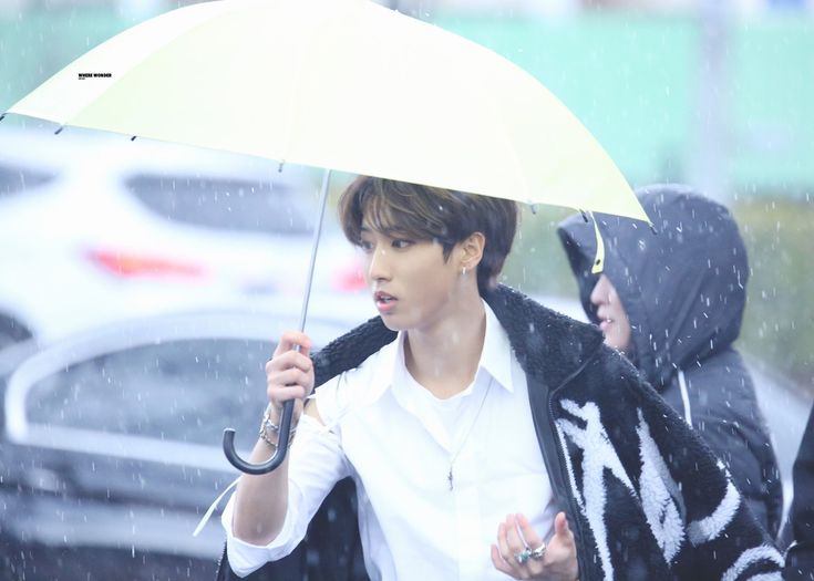 a person walking in the rain with an umbrella over their head and two other people behind them