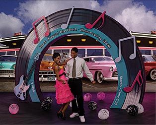 a man and woman standing in front of a stage with musical notes on the wall