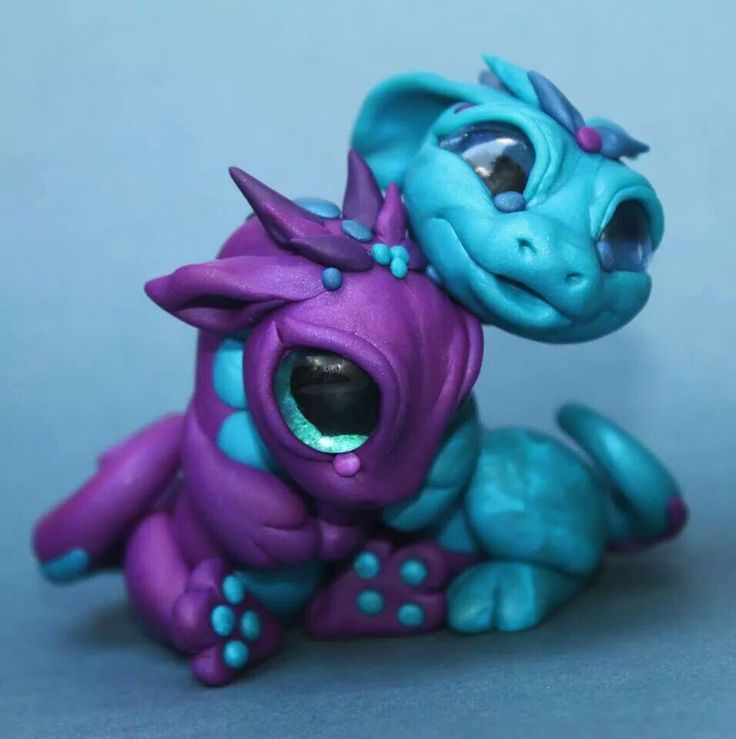 a purple and blue dragon figurine sitting on top of a gray surface with its mouth open