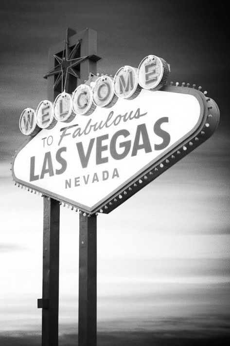 a black and white photo of the welcome to fabulous las vegas sign in front of a cloudy sky